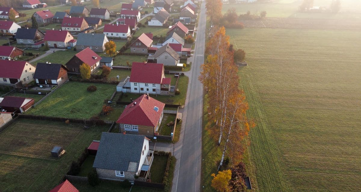 Widok z drona na skraj polskiej wsi: domy przy drodze i niezabudowane działki — od 1 września 2026 r. o warunkach zabudowy dla takich terenów decyduje plan ogólny gminy